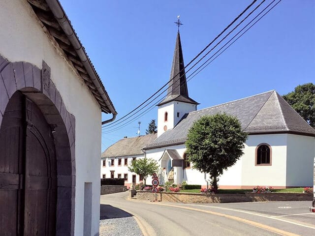 Hoeve in Herresbach doorzicht op de plaatselijke kerk